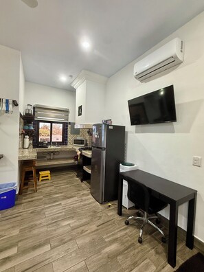 A compact kitchen with a refrigerator, microwave, and a flat-screen TV mounted on the wall. - Cozy 1-bedroom studio in perfect Isla Mujeres with AC (Isla Mujeres)
