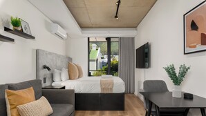 Une chambre moderne avec un lit, un canapé, un bureau et une vue sur un paysage verdoyant.