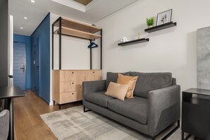 Ein modernes Wohnzimmer mit einem grauen Sofa, einem Holzschrank und einer blauen Tür.