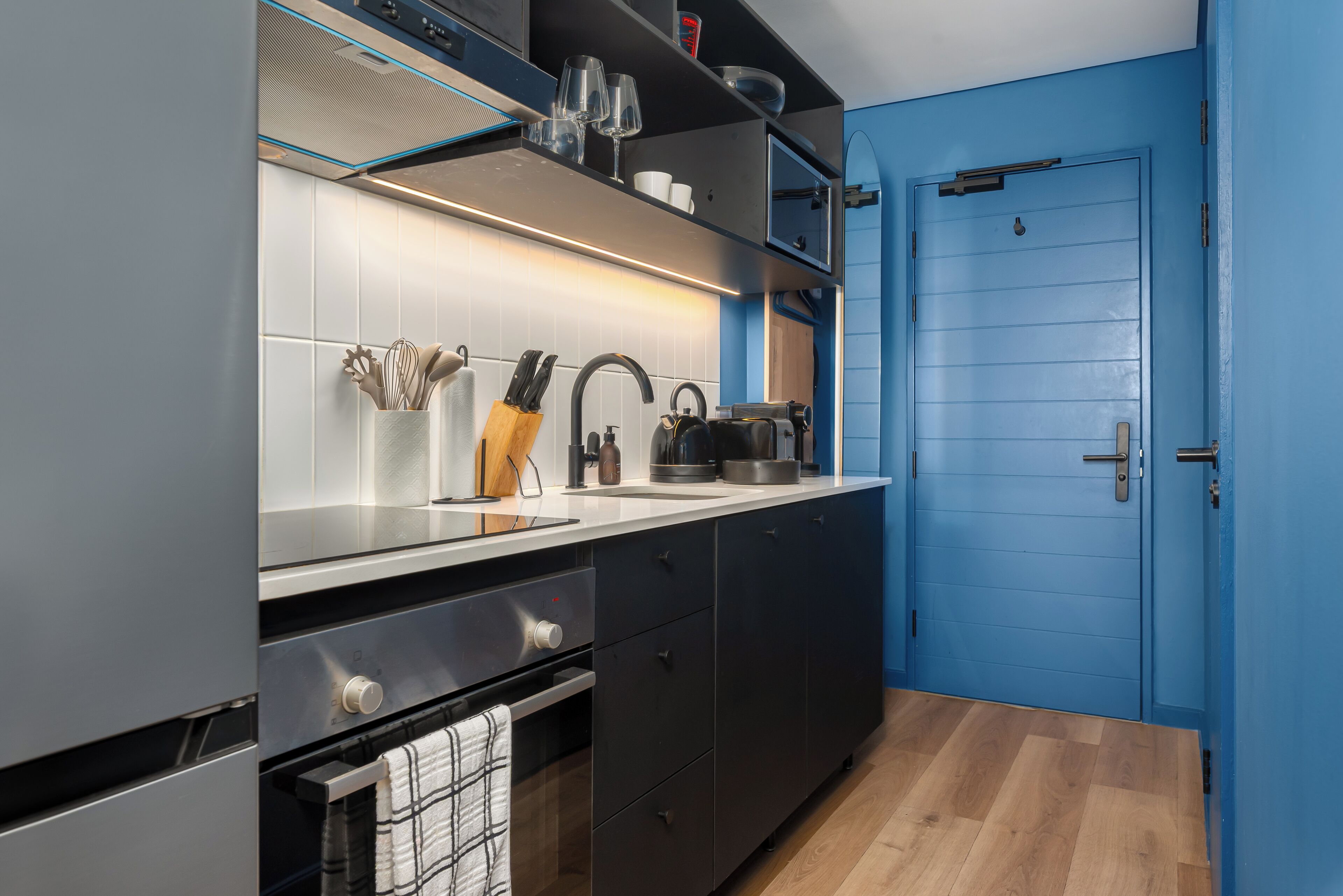 A modern kitchen with a built-in oven, a sink, and a coffee machine.
