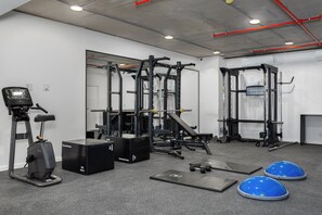 Ein Fitnessstudio mit Trainingsgeräten, darunter Laufbänder, Kraftgeräte und Matten.