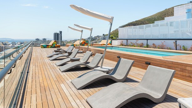 Une terrasse ensoleillée avec des chaises longues et une piscine.