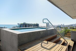 A rooftop pool with a city view, wooden deck, and a metal railing. - Stylish Sea Point Studio (Cape Town)