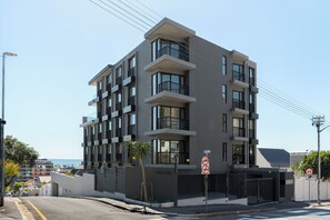 A multi-story building with balconies, a gated entrance, and a clear sky. - Stylish Sea Point Studio (Cape Town)
