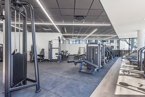 A gym with various exercise equipment, including treadmills and weight machines. - One Rosebank | Elevated Urban Comfort (Johannesburg)