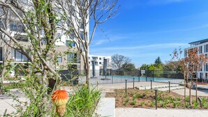 A modern building with a swimming pool, surrounded by trees and a well-maintained garden. - One Rosebank | Elevated Urban Comfort (Johannesburg)