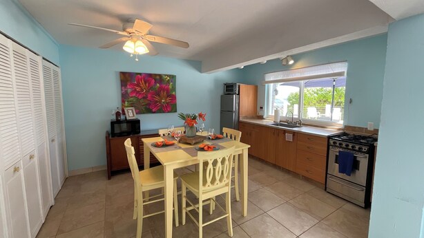 A kitchen with a dining area, a ceiling fan, a refrigerator, a stove, and a window with a view.
