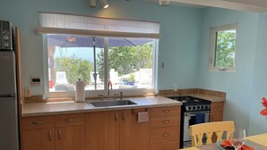 A kitchen with wooden cabinets, a sink, a stove, and a dining area with a table and chairs.