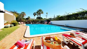 A swimming pool with lounge chairs and a dining setup. - Villa with Pool and BBQ near Galé Beach (Albufeira)