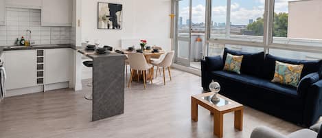 A modern living space with a kitchen, dining area, and a sofa with a city view.