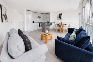 Ein modernes Wohnzimmer mit einem grauen Sofa, einem blauen Sofa und einem Couchtisch aus Holz.