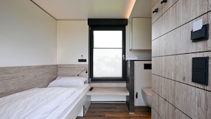 Un dormitorio moderno con cama, un escritorio pequeño y un armario.