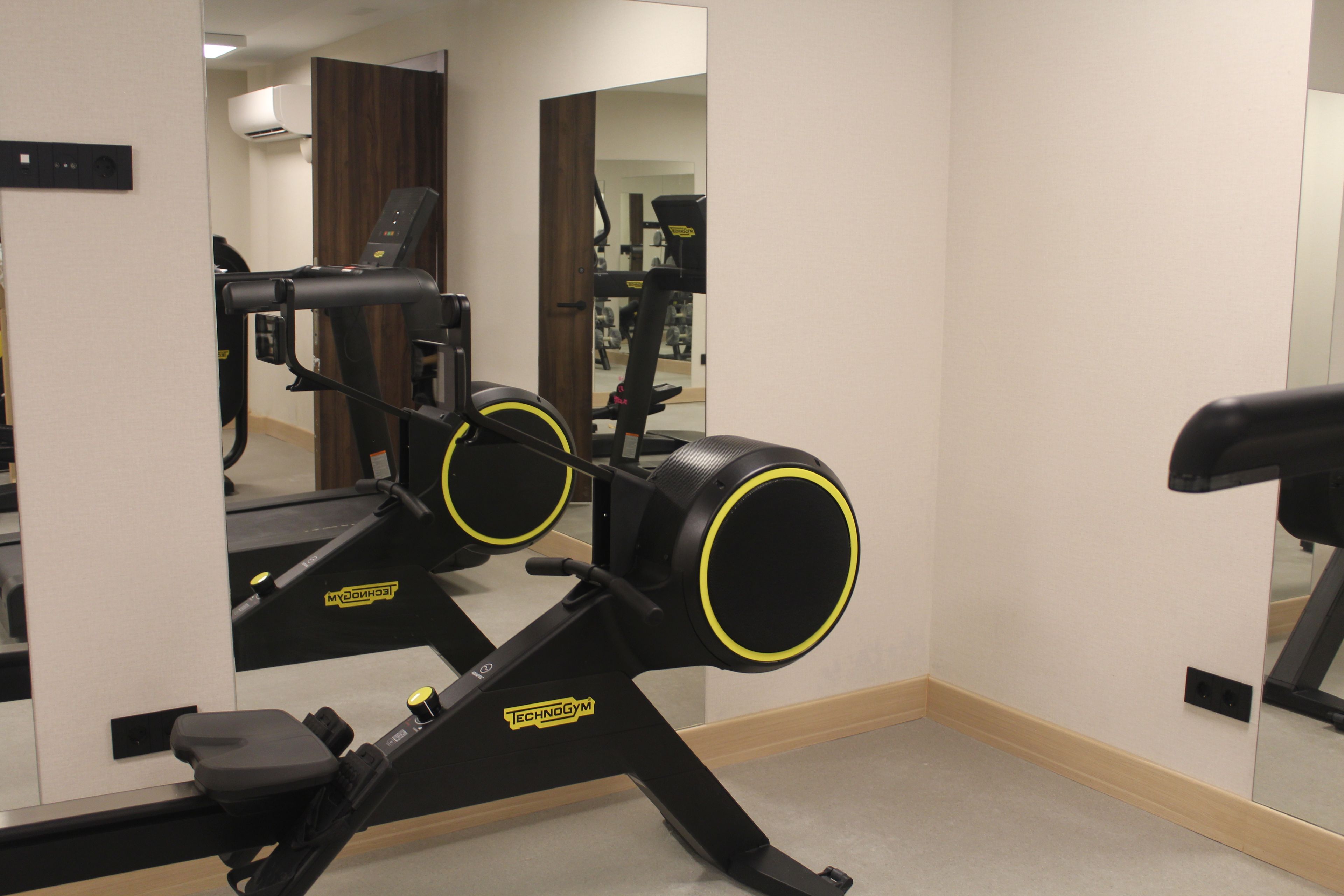 Une salle de sport équipée de matériel d’exercice, notamment un vélo d’appartement et un tapis de course.