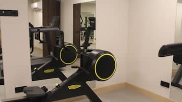 Une salle de sport équipée de matériel d’exercice, notamment un vélo d’appartement et un tapis de course.
