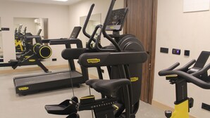 Een sportschool met diverse fitnessapparaten, waaronder loopbanden en elliptische trainers.