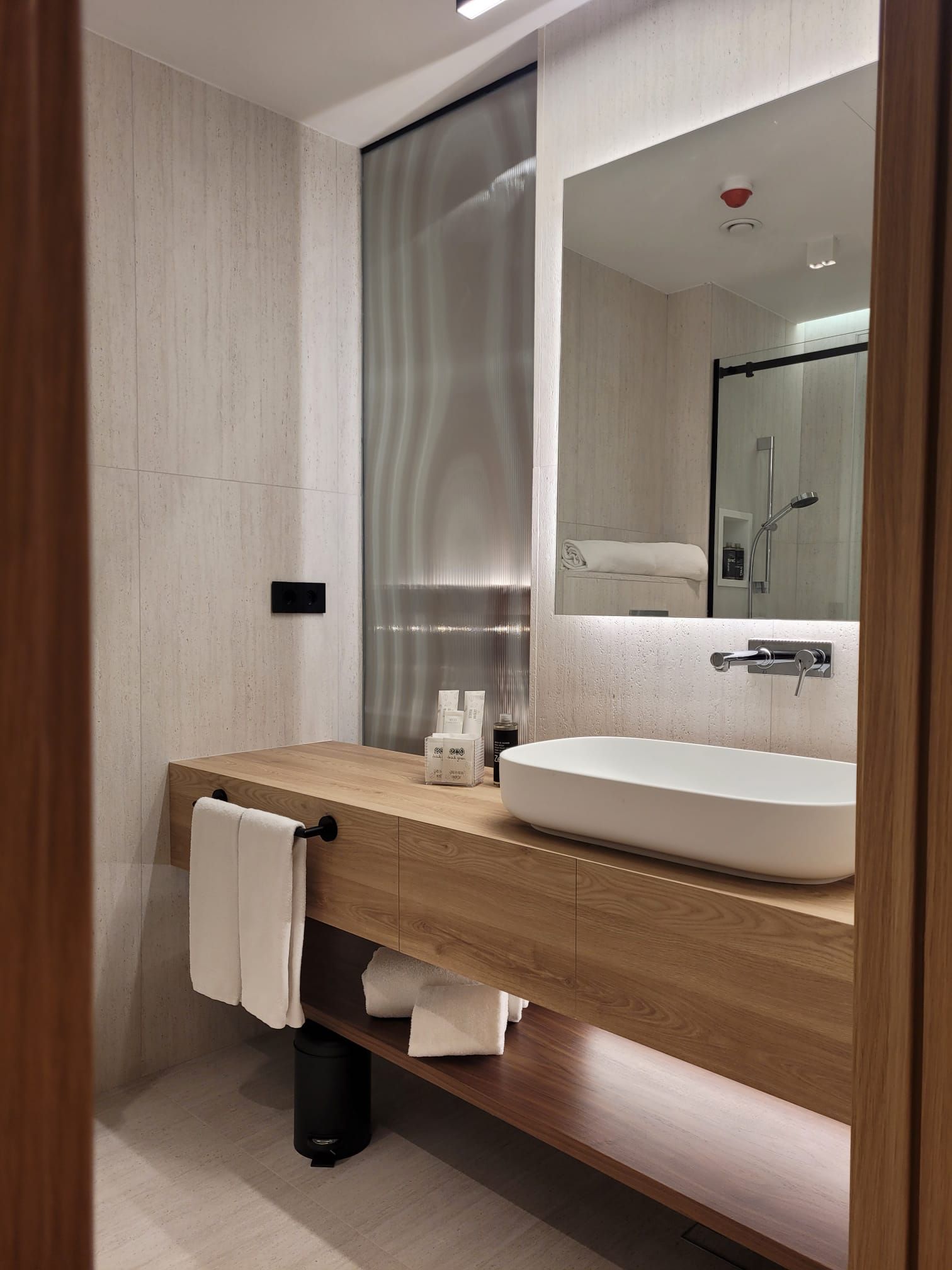 Un baño moderno con tocador de madera, un espejo grande y ducha integrada.