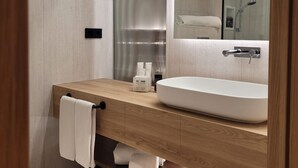 Een moderne badkamer met een houten wastafelmeubel, een grote spiegel en een inloopdouche.