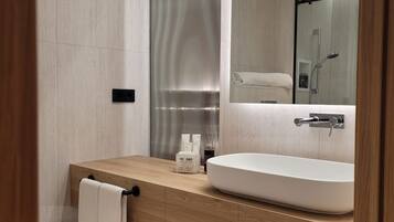 Un baño moderno con tocador de madera, un espejo grande y ducha integrada.