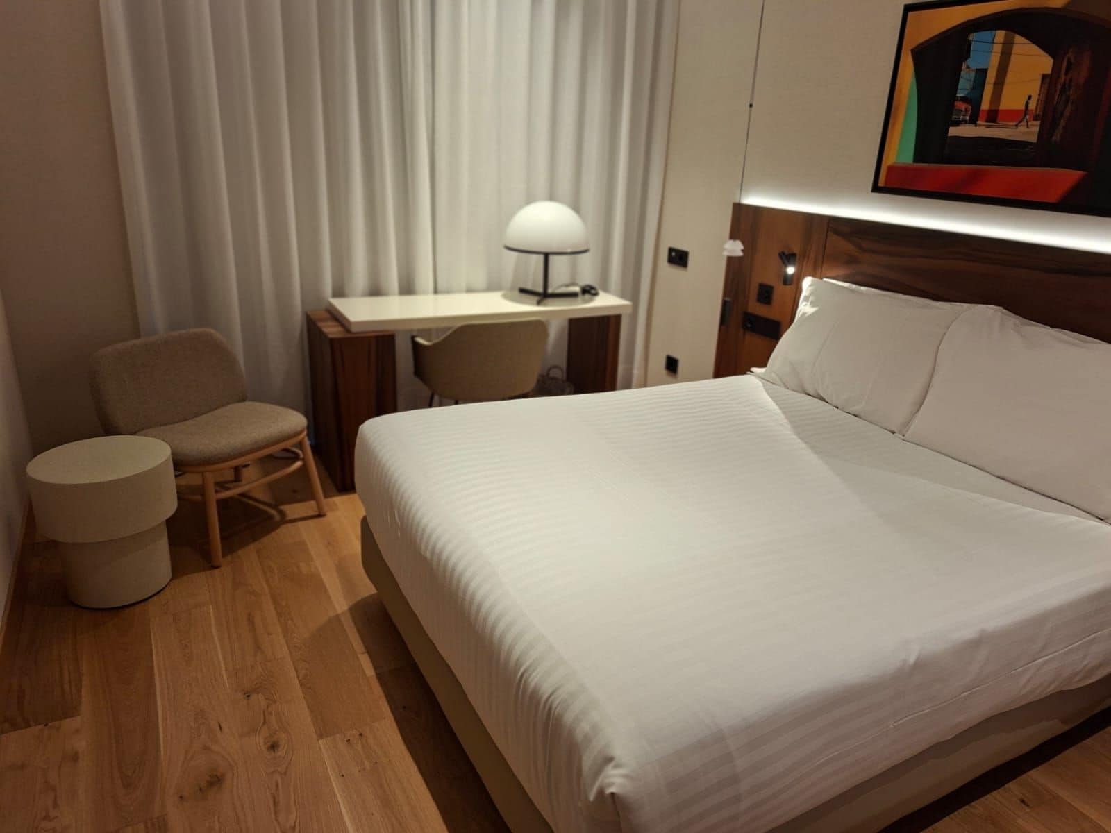 Une chambre d’hôtel avec un lit, un bureau, une chaise et une lampe.
