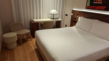 Une chambre d’hôtel avec un lit, un bureau, une chaise et une lampe.