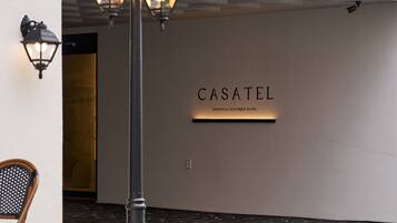 A hallway with a sign reading 'CASATEL EUROPEAN BOUTIQUE HOTEL' and a chair to the left.