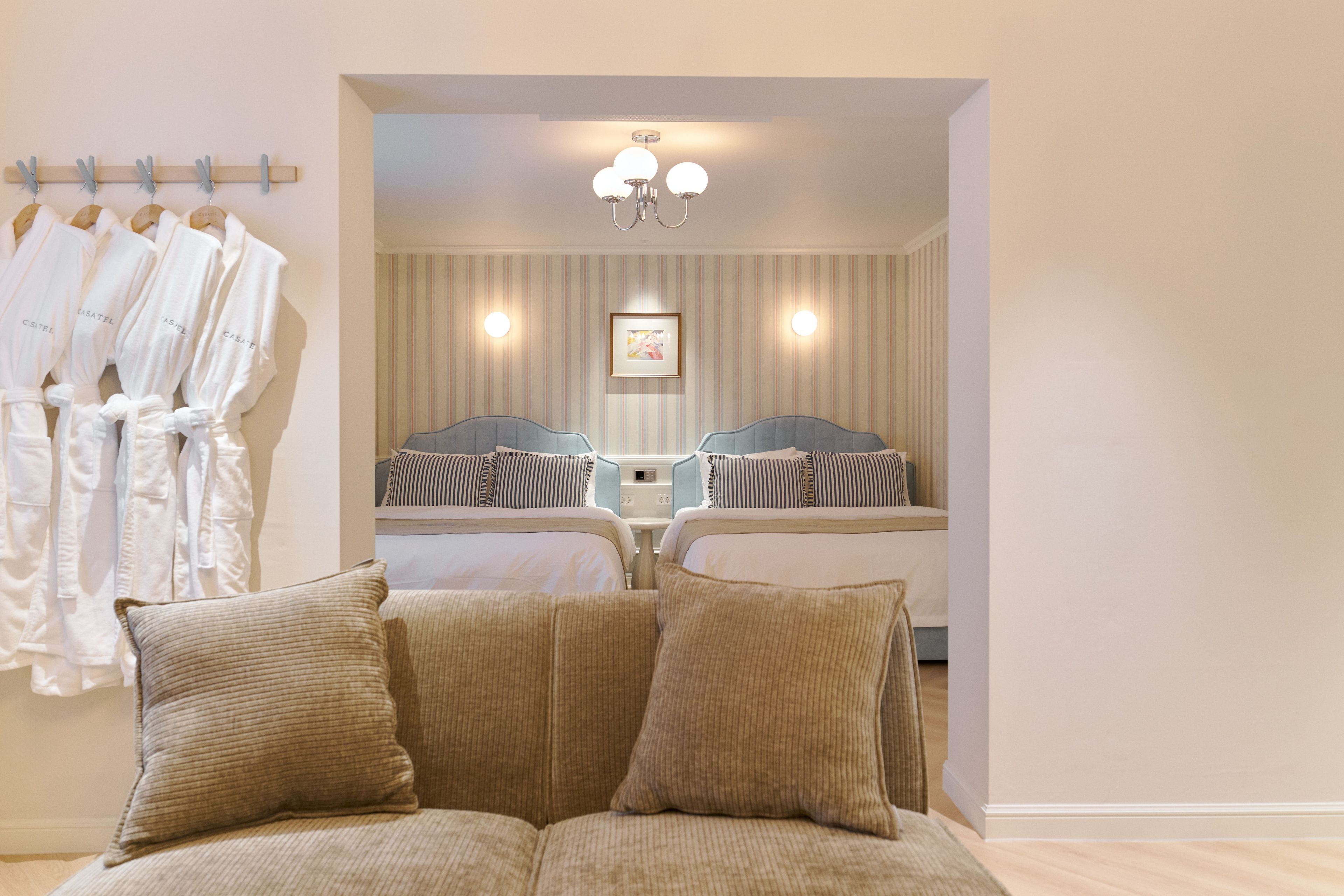 A hotel room with a bed, two bedside tables, a mirror, and a seating area with cushions.