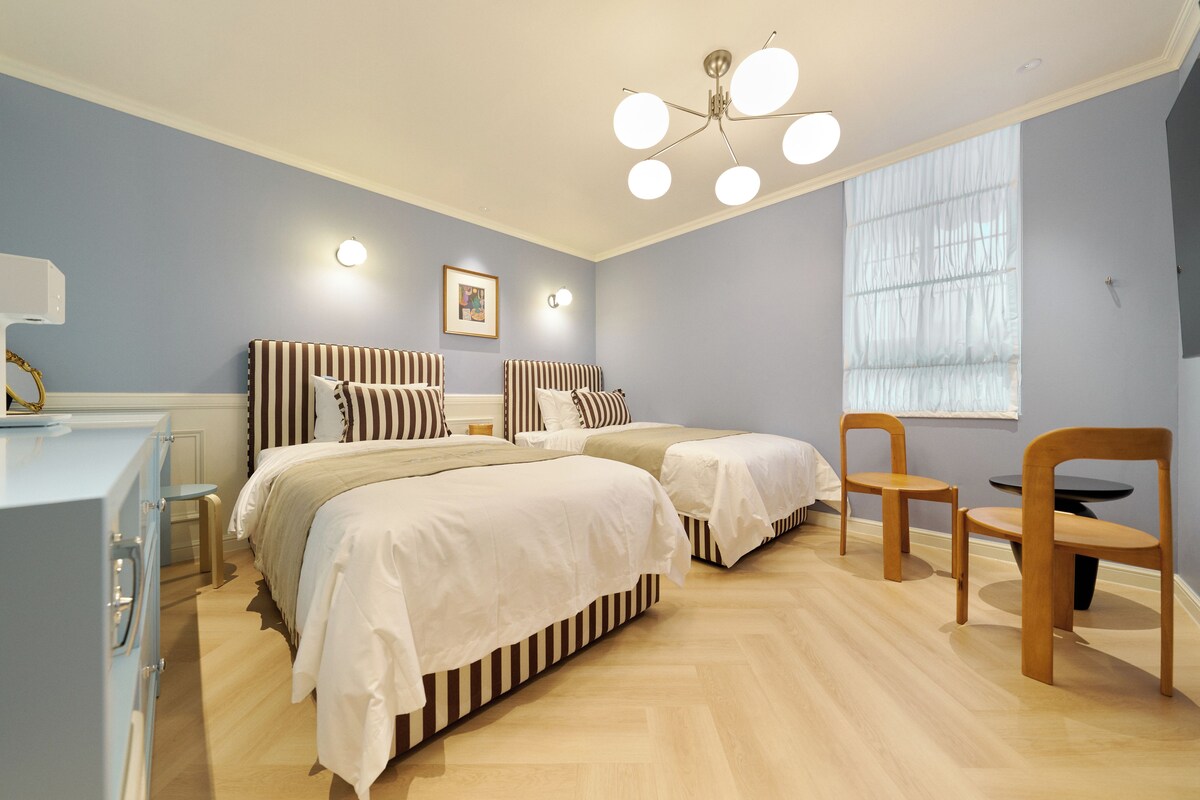 Un dormitorio con dos camas, un escritorio y una silla.