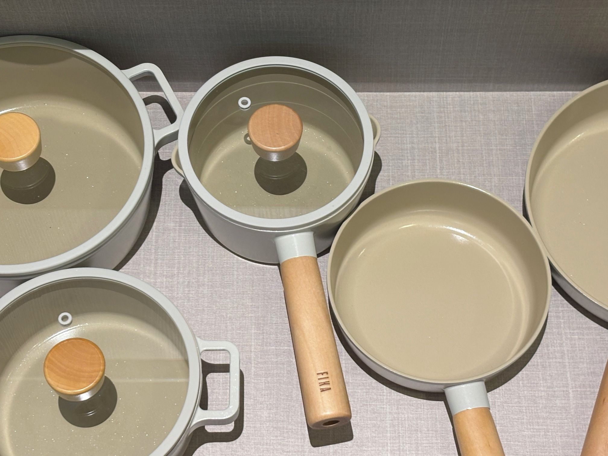 Un juego de utensilios de cocina con mangos y tapas de madera, sobre una superficie textil.