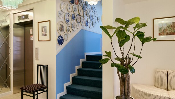 A staircase with blue steps, a potted plant, a chair, and a wall with decorative plates. - Casatel Jeonju Hanok Village (Jeonju)