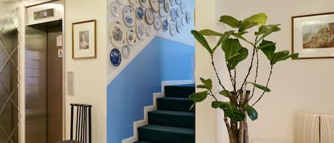 Una escalera con peldaños azules, una planta en maceta, una silla y una pared con platos decorativos.