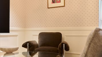 Una habitación con un sillón marrón, una mesa de vidrio y un cuadro en la pared.