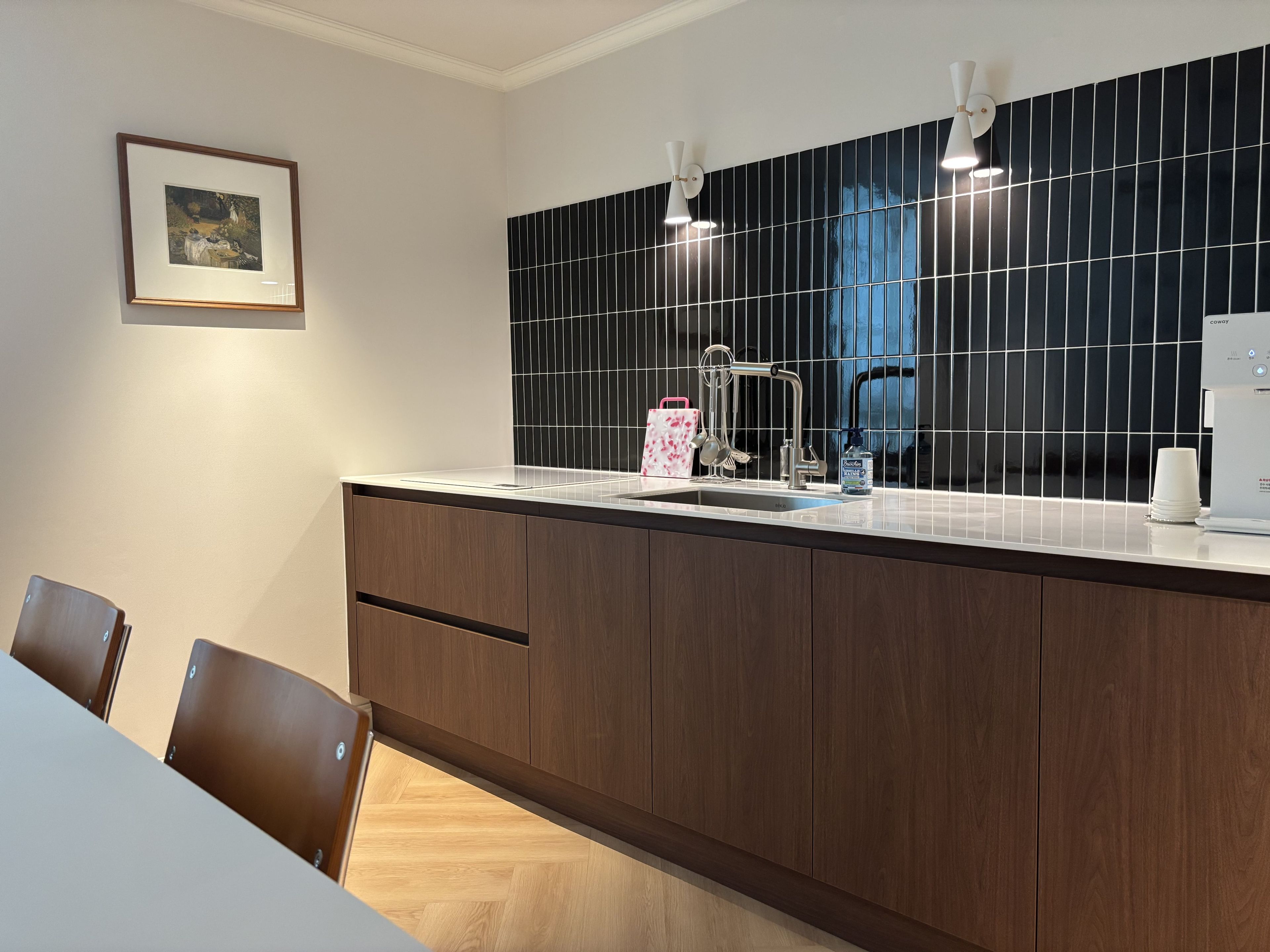 A modern kitchen with a black tiled backsplash, stainless steel appliances, and a wooden cabinet.