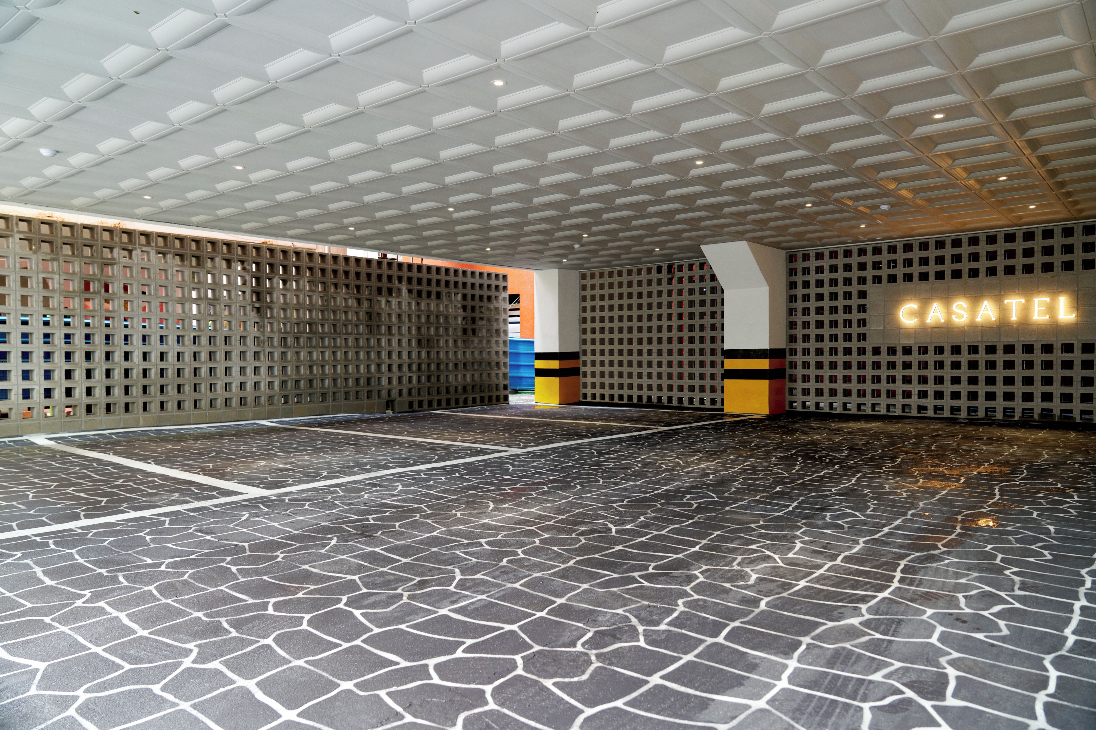 Un espacio interior amplio con piso estampado e iluminación empotrada en el techo.