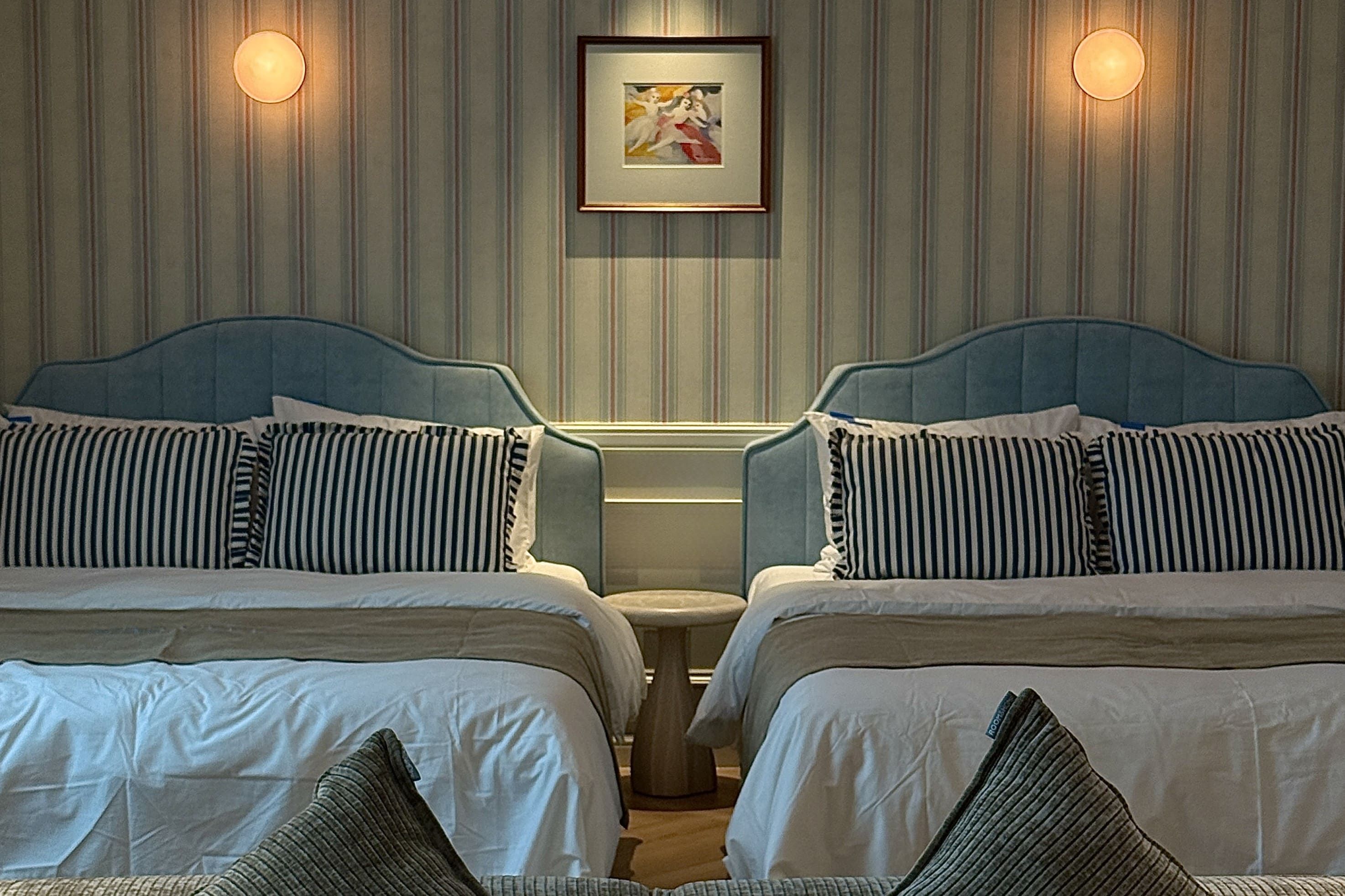 A hotel room with two beds, striped bedding, and a framed picture on the wall.