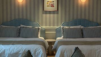 A hotel room with two beds, striped bedding, and a framed picture on the wall.