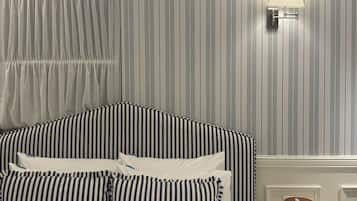 Habitación de hotel con papel tapiz a rayas, cama con ropa de cama a rayas, lámpara de noche y una caja de pañuelos.