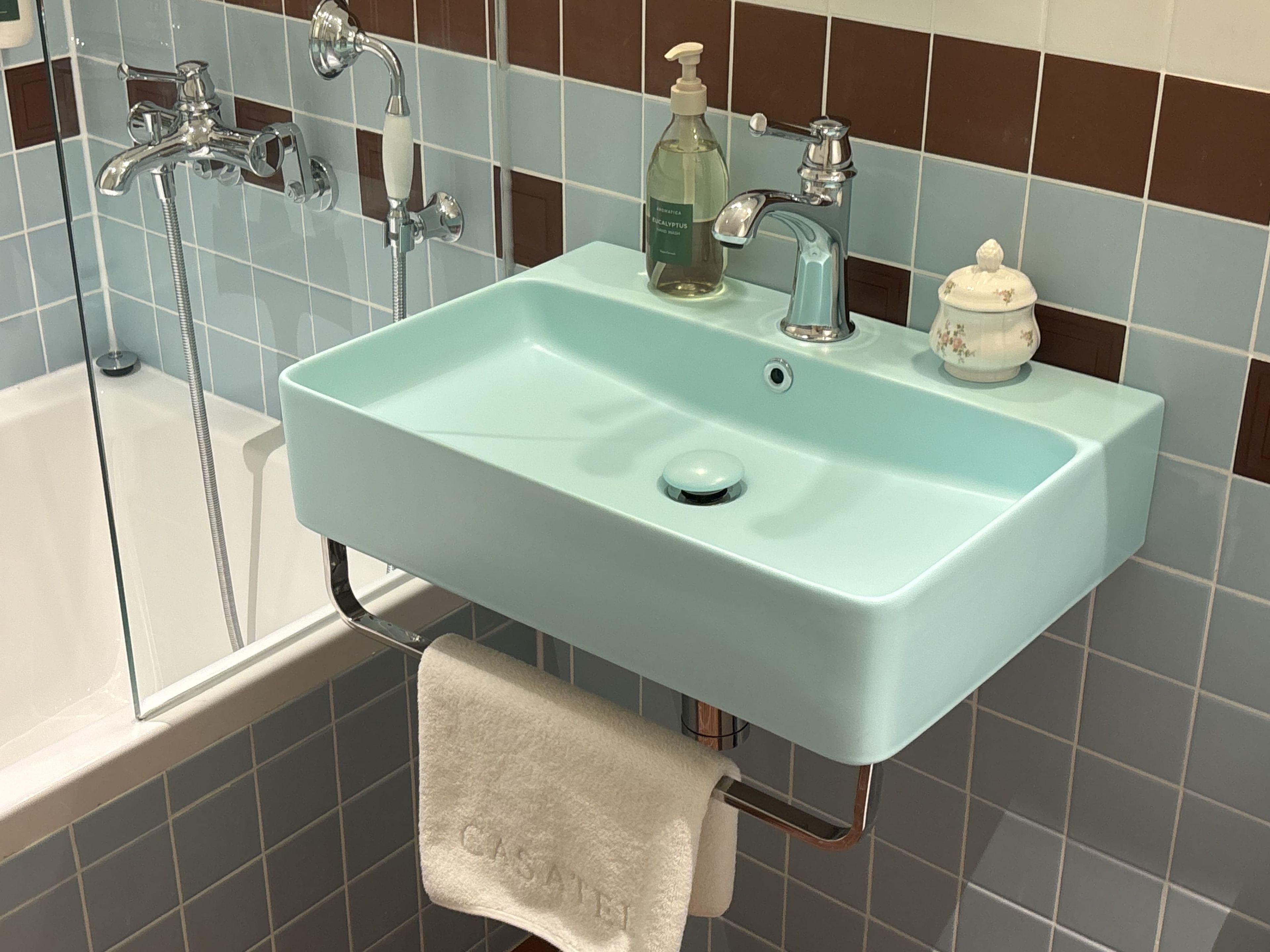 Un baño con un lavamanos azul claro, una bañera blanca y una ducha.