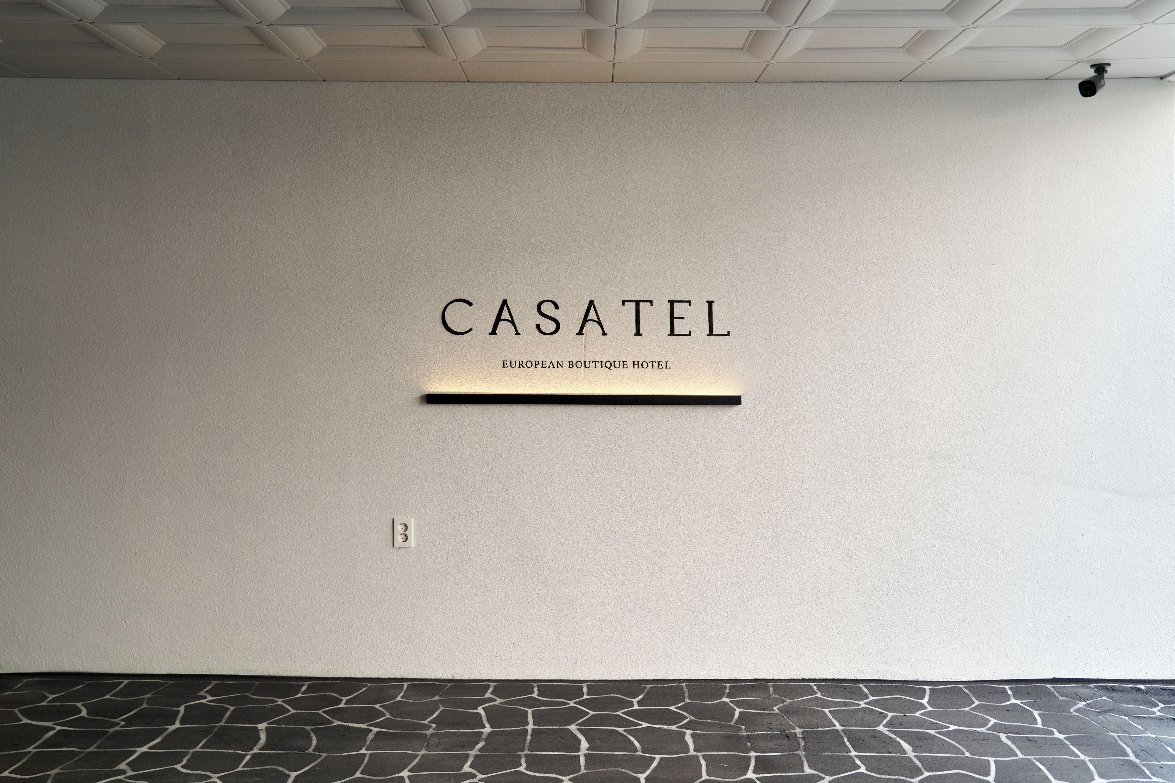 Una pared con el texto 'CASATEL' y 'HOTEL BOUTIQUE EUROPEO', indicando el nombre del establecimiento.
