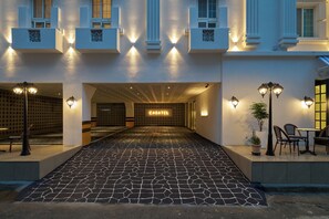 A hotel entrance with a tiled walkway leading to a covered area.