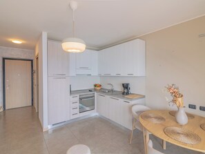 A modern kitchen with white cabinets, a built-in oven, and a coffee maker. - EnjoyIseoLake - Lake Horizon (Plassi)