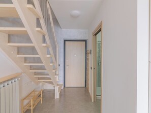 Ein modernes Interieur mit einer Holztreppe, einer Tür mit Glasfenster und einem gefliesten Boden.