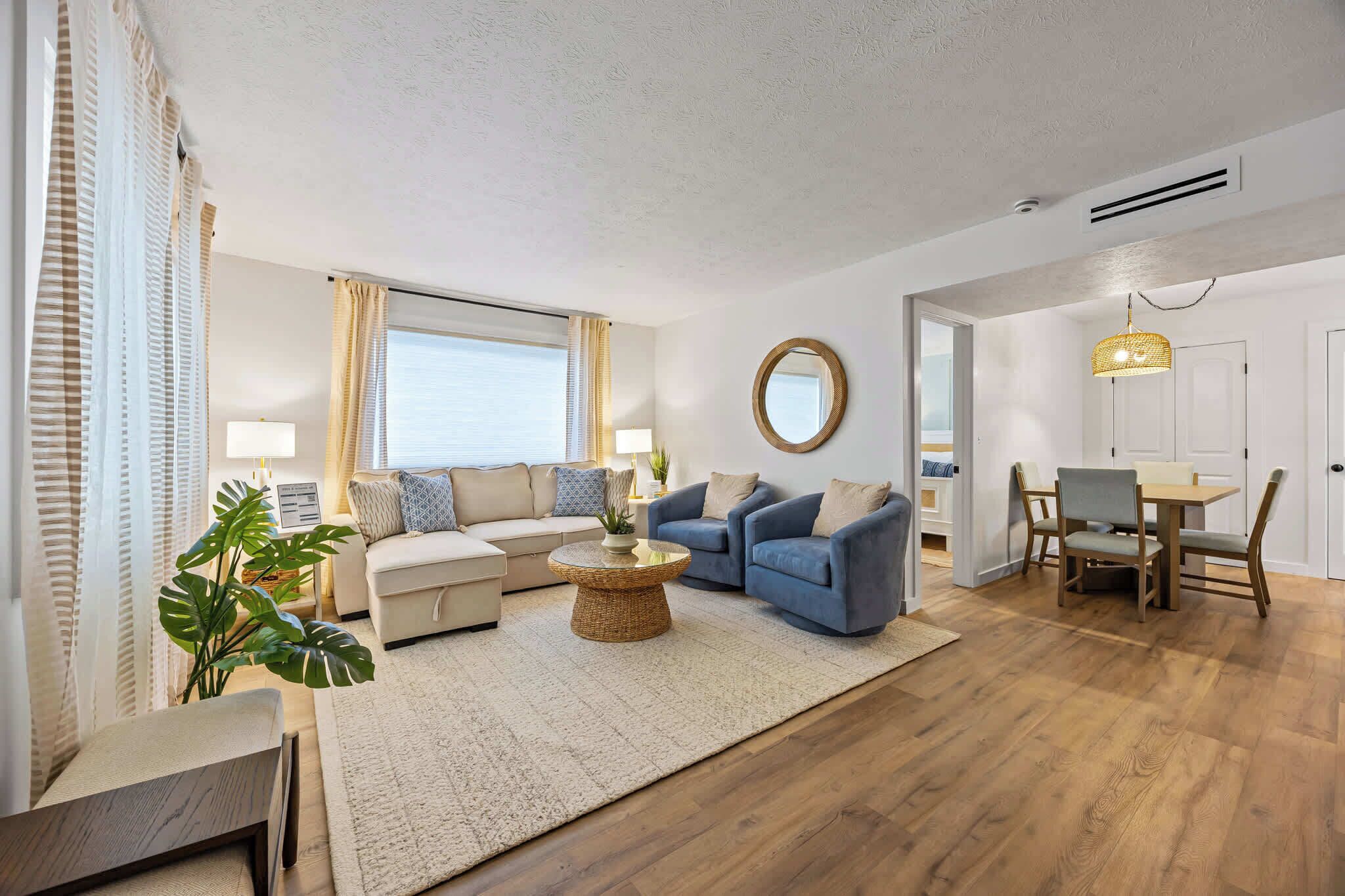 A modern living room with a sofa, a coffee table, and a dining area with a table and chairs.