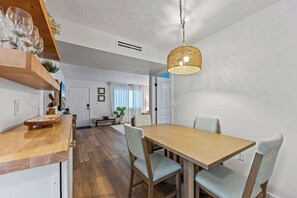 En matplats med ett träbord och stolar, en hängande lampa och ett köksområde med en träbänkskiva och skåp.
