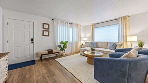 Ein stilvolles Wohnzimmer mit einer Couch, Sesseln, einem Couchtisch und einem Essbereich.