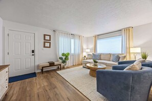Ein stilvolles Wohnzimmer mit einer Couch, Sesseln, einem Couchtisch und einem Essbereich.