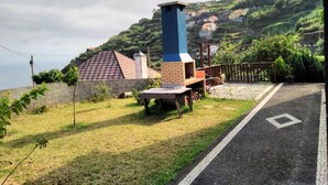 A residential area with a prominent chimney, a paved road, and a view of houses on a hillside. - Villa 'Quinta Do Serrado' with Sea View, Private Garden and Wi-Fi (Ribeira da Janela)