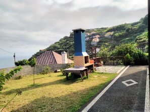A residential area with a prominent chimney, a paved road, and a view of houses on a hillside. - Villa 'Quinta Do Serrado' with Sea View, Private Garden and Wi-Fi (Ribeira da Janela)