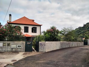 A two-story house with a red-tiled roof, a gated entrance, and a stone wall. - Villa 'Quinta Do Serrado' with Sea View, Private Garden and Wi-Fi (Ribeira da Janela)