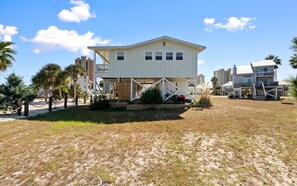 A two-story beachfront property with a covered patio, a small deck, and a staircase leading to the upper level. - Lagoon Access, Short Walk to the beach, Sleeps 10! (Gulf Shores)