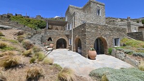 Un edificio de piedra con un patio, arcos y una escalera que sube.